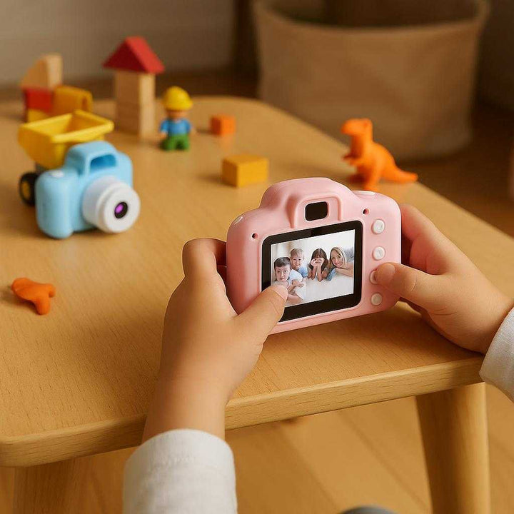 Produkter til Krøller med Høj Kvalitet og Avanceret Funktionalitet - Børnekamera i Blå og Pink: A realistic playroom setting where the camera is properly grounded on a child-sized table, actively used by a child's small hands, capturing spontaneous moments with toys scattered around.