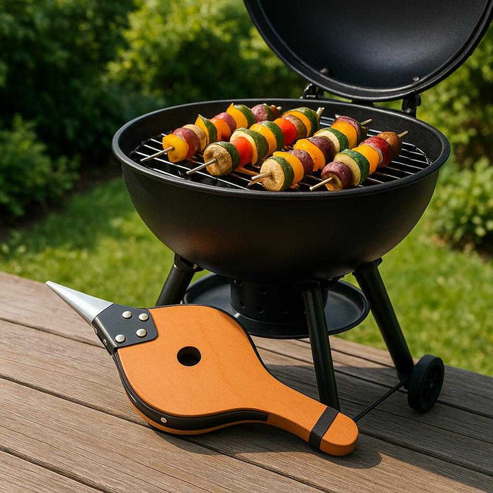 Professionel Blæsebælg i Træ – Klassisk og Høj Kvalitet Design til Pejs og Grill. A high-quality wooden bellows rests elegantly next to a modern outdoor grill, surrounded by a lush green garden setting, with skewers of vegetables grilling in the background.