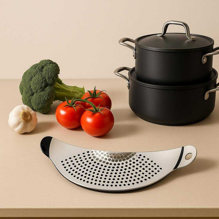 Professionel Grydesi i Rustfrit Stål - Høj Kvalitet, Pladsbesparende Design til Alle Gryder. A minimalist kitchen scene showing the sleek pot lid resting on a counter next to fresh vegetables and a neatly arranged set of cookware, highlighting its space-saving design.