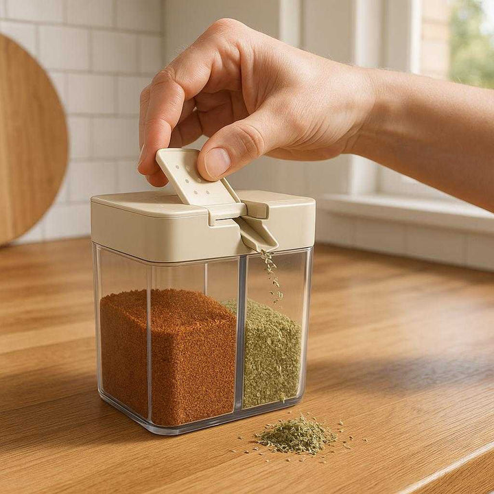 Professionel Krydderibøtte med Dobbelt Låg, Transparent Beholder og Høj Kvalitet: A realistic modern kitchen setting where the product is properly grounded on a wooden countertop, being actively used to dispense spices by a person's hand pouring from one of the dual lids, with natural lighting from a window casting realistic shadows and showing clear contact points where the product touches the countertop.