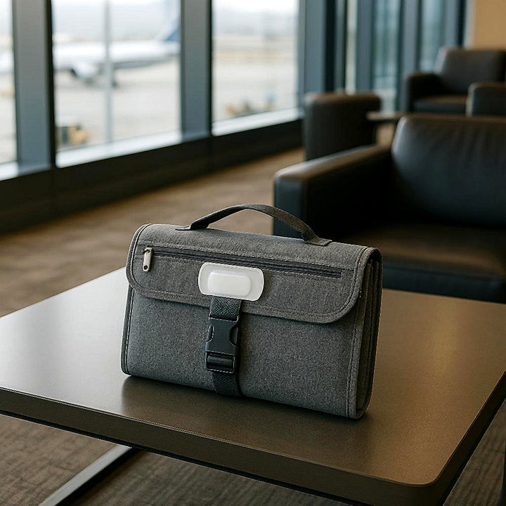 Rejsepusleunderlag - Kvalitetskomfort til bleskift i stilfuld grå og blå: A realistic airport lounge setting where the product is properly grounded on a sleek, modern coffee table, being naturally placed and ready for use as a convenient travel accessory.