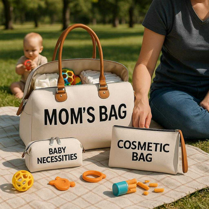 Rejsetasker i Lærred, Læder og Metal Lynlåse - Flere Rum, Let at Bære, Stilfuldt Design: A realistic park setting where the large bag is properly grounded on a picnic blanket, surrounded by baby toys and snacks, actively used by a parent sitting next to it, looking after a child playing nearby.