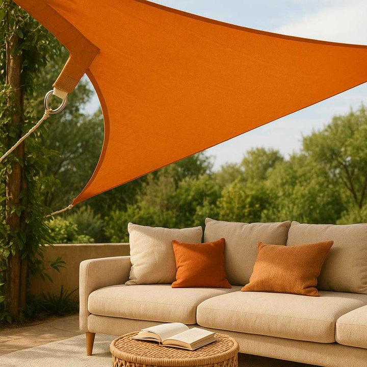 Rektangulært Solsejl Vandtæt UV-beskyttende Overdækning i Orange og Beige - Høj Kvalitet og Holdbarhed. A cozy outdoor lounge area with the durable orange and beige sun sail elegantly draped above, providing shade and creating a relaxing spot with cushions and a book on a small table.