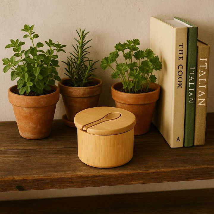 Saltkrukke i Træ med Låg og Ske - Naturlig og Elegant Opbevaring til Køkkenet. A cozy kitchen setting featuring the stylish wooden salt cellar on a rustic wooden shelf surrounded by potted herbs and cookbooks.