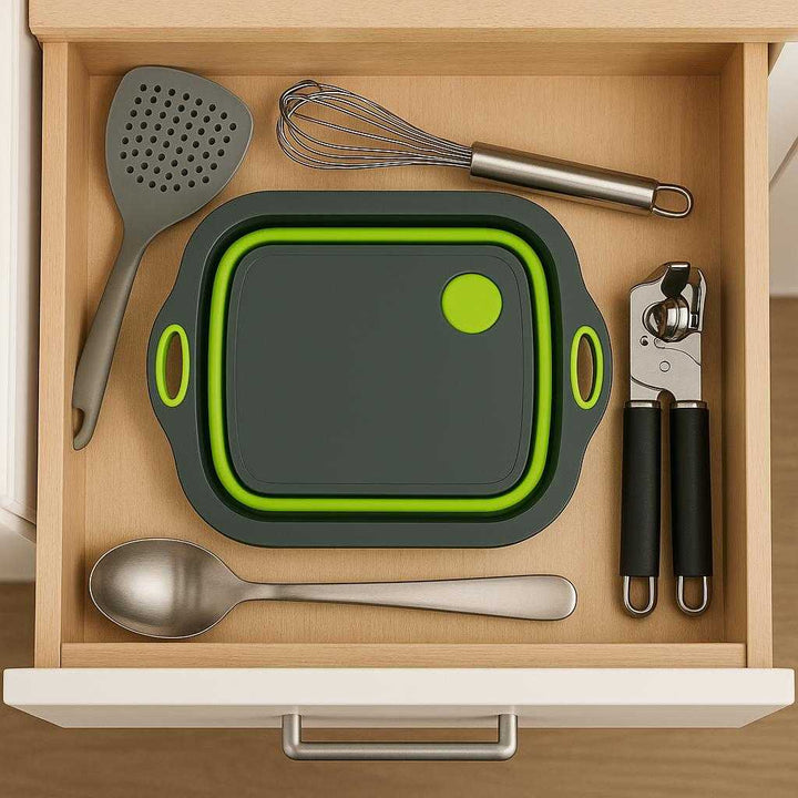 Sammenklappeligt skærebræt med afløb og håndtag – Multifunktionelt og Pladsbesparende Design i Moderne Grå og Lysegrøn. The multifunctional cutting board is effortlessly folded and stored in a compact drawer, surrounded by other kitchen utensils, showcasing its space-saving design.
