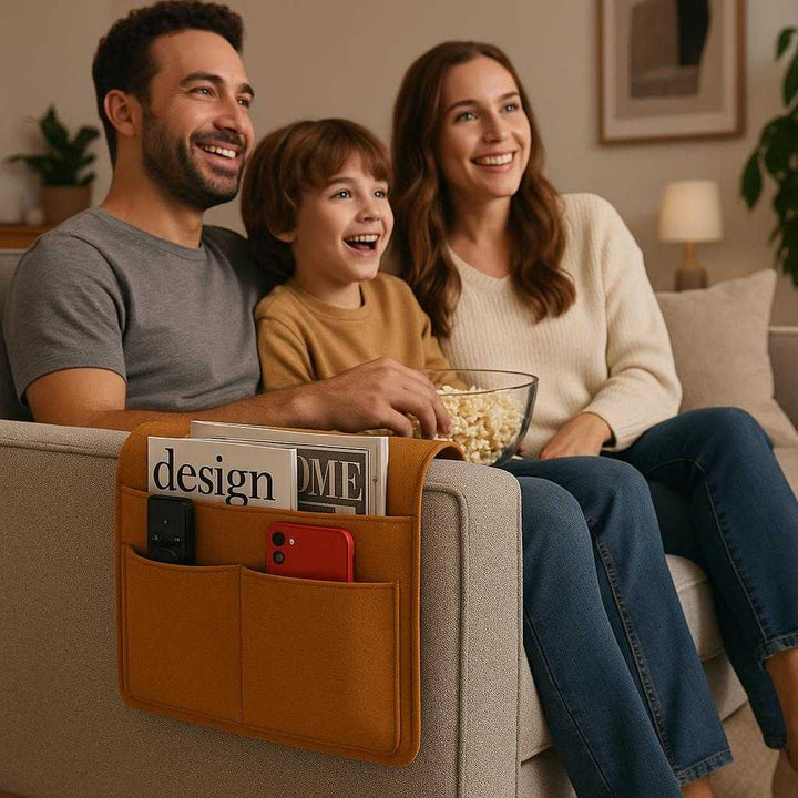 Sengeopbevaring i Filt med Lommer - Praktisk og Elegant i Brun, Lysegrå, Sort. In a modern living room, the versatile brown felt storage organizer is hanging from a sofa armrest, storing a TV remote and magazines, while a family enjoys a movie night.