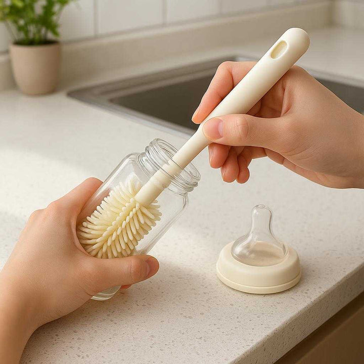 Silikone Flaske Børste - Beige & Ny Grøn, Plastik & Silicone, Udskiftelige Børstehoveder: A realistic kitchen countertop setting where the Silikone Flaske Børste is being actively used by a person's hands to clean a baby bottle.