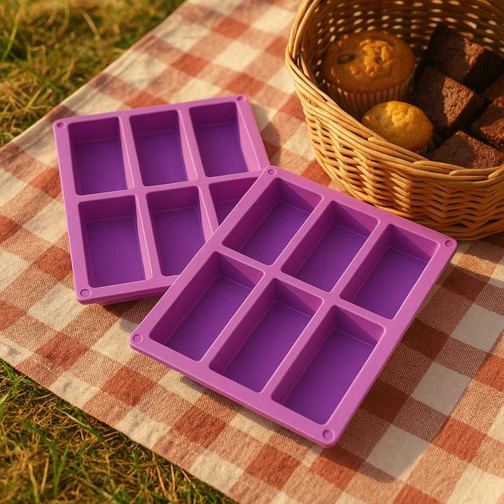 Silikone 'granola bar" → "müslibar' = 'Granola-bar' forme, lilla, fleksibel, non-stick, tåler høje temperaturer, 2 stk.: A different realistic picnic setting where the product is securely positioned on a checkered picnic blanket, naturally placed next to a basket with other homemade treats.