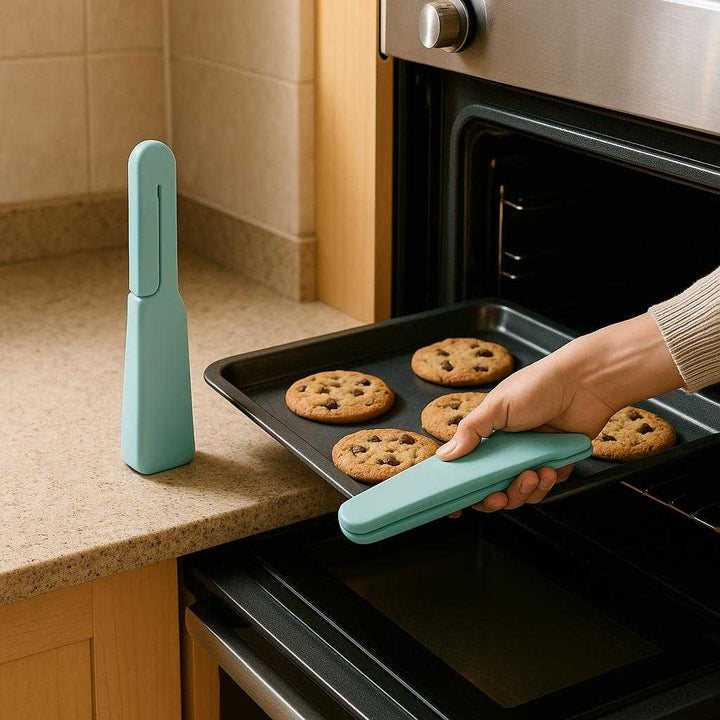 Silikone Grydelap - Høj Varmebestandighed - Rød, Hvid, Sort, Blå, Grøn, Mørkeblå: A realistic kitchen setting where the silicone oven mitt is properly grounded on a countertop beside a hot oven, being actively used by a person's hand to safely remove a freshly baked tray of cookies.