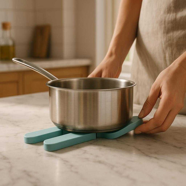 Silikone Grydelap - Høj Varmebestandighed, Moderne Design, Tilgængelig i 6 Farver: A realistic contemporary kitchen setting where the silicone grydelap is properly grounded on a marble countertop, being actively used by a person placing it under a hot saucepan.