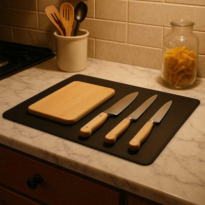 Skrivebordsmåtte i læder - Moderne design, nem at rengøre, anti-træthed, tilgængelig i 7 farver: A different realistic kitchen setting where the leather desk mat is securely positioned on a marble countertop, used as a protective surface for organizing essential kitchen tools like knives and a cutting board.