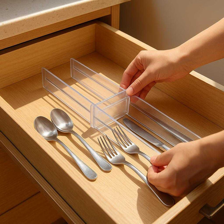 Skuffeopdeler i justerbar plast tilbehør – Organisér nemt og effektivt i hjemmet: A realistic kitchen drawer setting where the drawer divider is properly grounded inside a wooden drawer, being actively adjusted by a pair of hands to organize cutlery into separate compartments.
