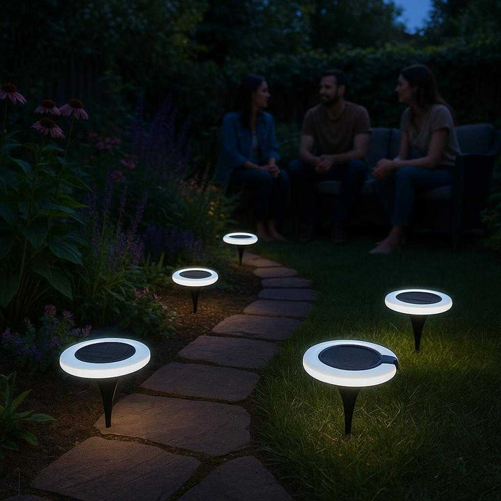 Solcellelamper til Haven: Moderne og Energieffektive LED Lys med Jordspyd og Vægophæng: A tranquil backyard garden at dusk, where the solar garden lights are elegantly placed along a stone pathway.