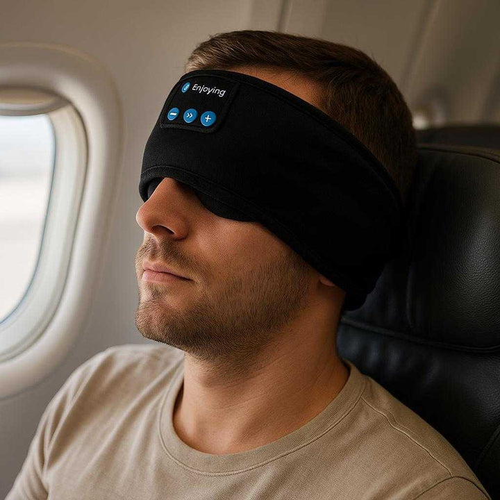 Sovemaske Med Bluetooth For Optimal Søvnkomfort, Avanceret Lydoplevelse Til Hjemmet Og Rejser: A different realistic airplane cabin setting where the mask is securely positioned on a passenger's head, used naturally during a flight, with natural cabin lighting creating soft shadows and realistic integration into the travel environment, suggesting comfort and relaxation.