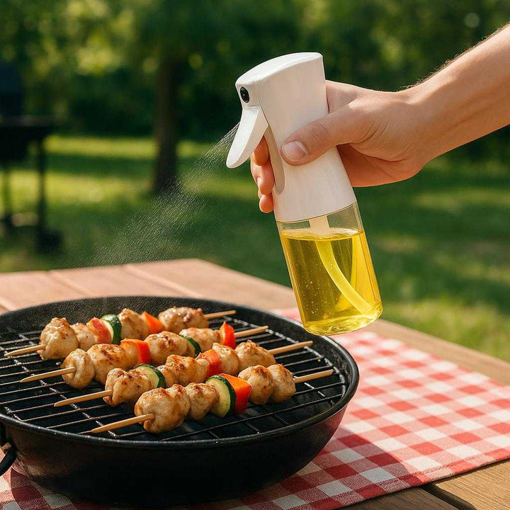 Sprayflaske til Olie med Præcis Dosering - Høj Kvalitet til Sundere Madlavning: A different realistic outdoor barbecue setting where the product is securely positioned on a picnic table, being used differently by a hand to spray oil onto a grilling rack with chicken skewers.