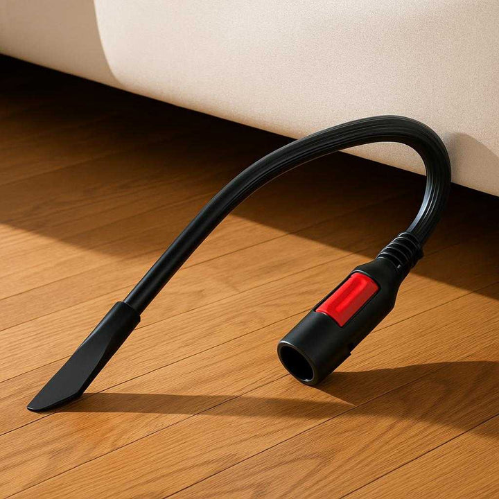 Støvsugermundstykke Fleksibelt Design - Optimal Rengøring Til Svære Områder. The versatile vacuum cleaner nozzle is effortlessly reaching under a low bed, with clean lines and shadows cast on a hardwood floor, highlighting its practical design.