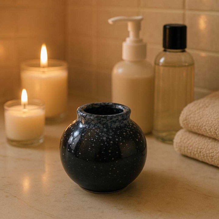 Tandstikkekrukke i keramik - Moderne og funktionel med glansfuld finish, Tilgængelig i Sort, Hvid, Brun. The ceramic holder is beautifully situated on a chic bathroom countertop, surrounded by elegant toiletries, reflecting soft ambient lighting as aromatic candles enhance a serene spa-like atmosphere.