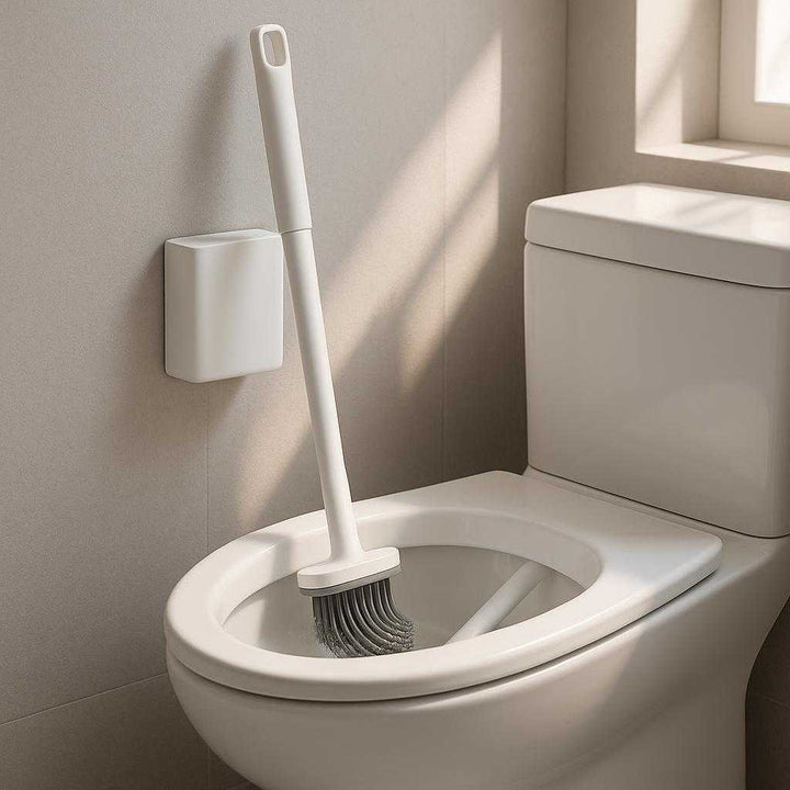 Toiletbørste i Moderne Design - Væghængt, Silikone, Tilgængelig i Hvid og Sort. The modern silicone toilet brush is mounted on a bathroom wall next to a sleek white toilet, with the bristles in action inside the bowl while a subtle ray of sunlight filters through a nearby window.
