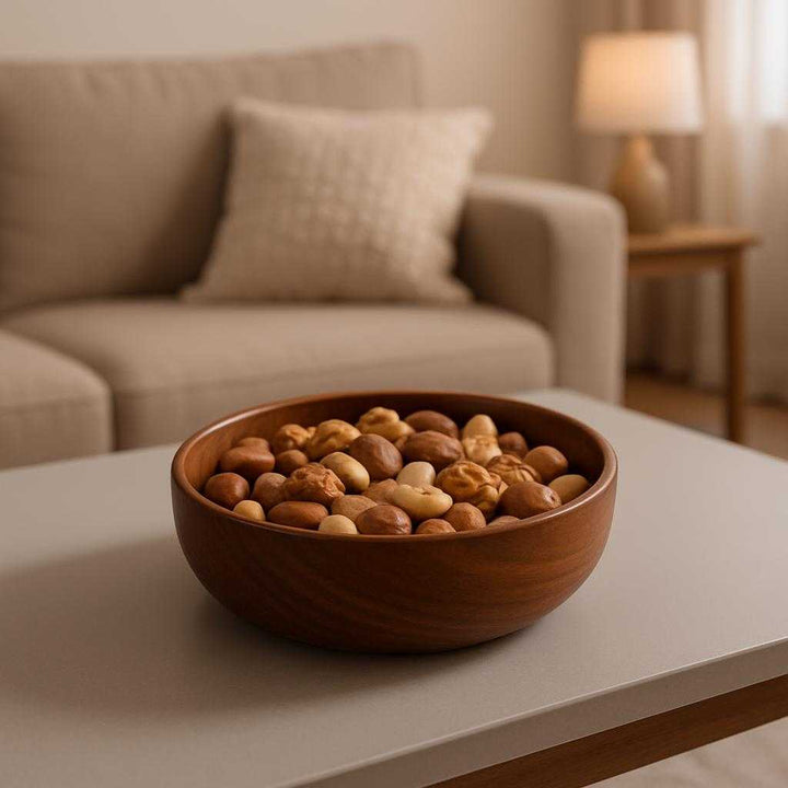 Træskål i valnøddetræ - Naturlig og elegant til servering og opbevaring. The stylish walnut wood bowl is beautifully presented on a modern dining table, filled with an assortment of nuts, with a cozy living room scene in the background.