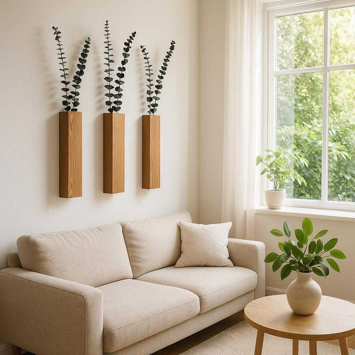 Trævægpotte i massiv træ - Moderne nordisk design til indendørs vægdekoration. The wooden wall vase is gracefully mounted in a bright, minimalist living room, with sunlight streaming through large windows and lush green foliage artistically displayed, creating a serene and stylish ambiance.