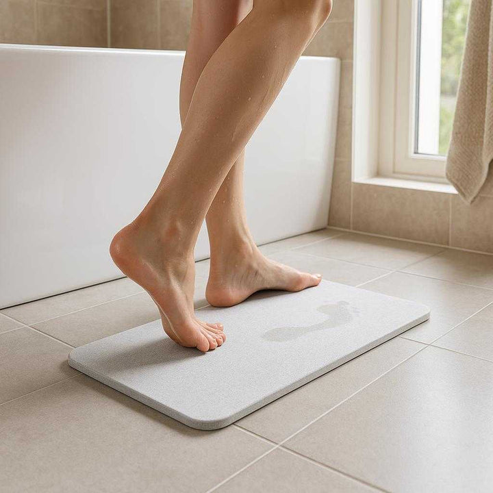 Vandabsorberende Stenmåtte – Kompakt Hurtigttørrende Bademåtte i Lys Grå til Badeværelset: A realistic bathroom setting where the Vandabsorberende Stenmåtte is properly grounded on a tiled bathroom floor in front of a bathtub.