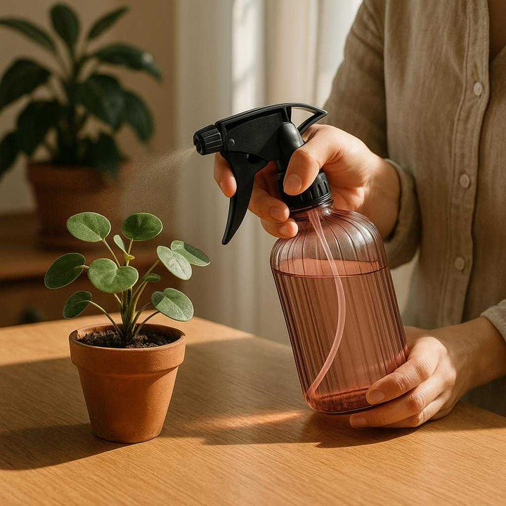 Vandkande i Plastik, Gennemsigtig, Let at Bruge, Justerbar Spray, God Kvalitet - Pink, Grøn, Grå 500ml: A realistic home gardening setting where the product is properly grounded on a wooden table, being actively used by a person to spray water onto a small indoor plant.