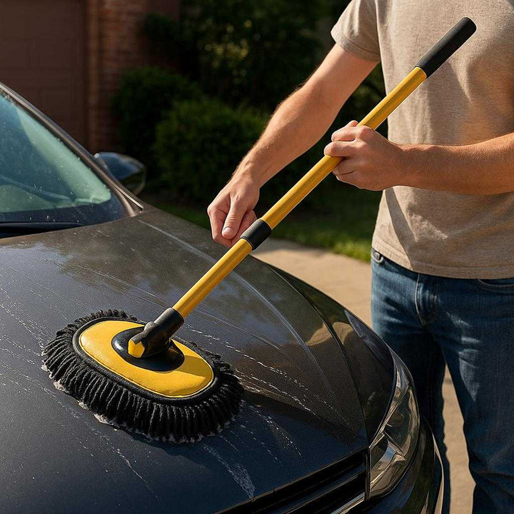 Vaskebørste Professionel Auto Vaskebørste til Skånsom Bilvask med Ergonomisk Design i Gule Nuancer: A realistic driveway setting where the Vaskebørste is properly grounded on a car hood, being actively used by a person to wash the car, with natural sunlight casting realistic shadows and showing clear contact points on the car surface.