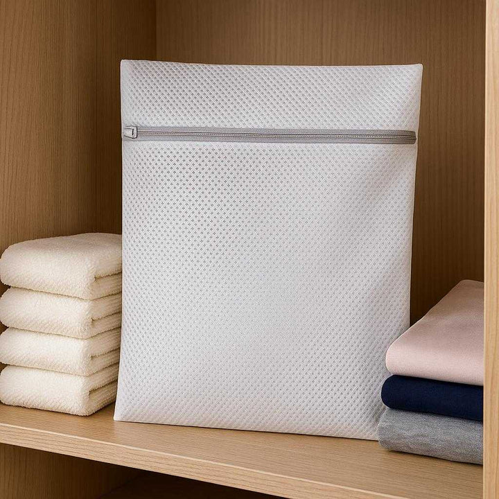 Vaskepose i høj kvalitet - Ideel til sko og større tekstiler, Beskytter tøj under vask, Tilgængelig i Medium og Large: A different realistic wardrobe setting where the bag is securely positioned on a shelf among neatly folded towels.