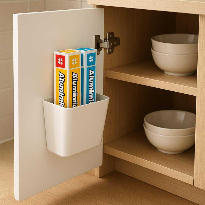 Væghængt opbevaringsholder i moderne design - Tilgængelig i Grøn og Hvid: A realistic kitchen setting where the modern design wall-mounted storage holder is properly grounded on the inside of a kitchen cabinet door, holding multiple colorful rolls of aluminum foil.