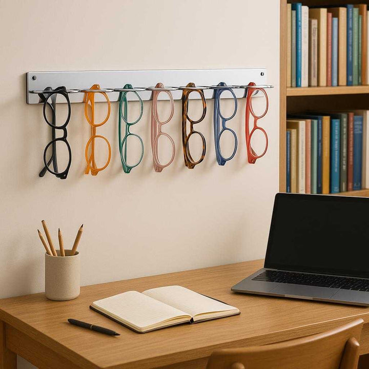 Vægmonteret Brilleholder i Stål - Elegant og Praktisk Opbevaring til Dit Hjem i Høj Kvalitet. A stylish study room features the steel eyewear holder mounted above a wooden desk, organized with colorful eyeglasses against a backdrop of books and a laptop.